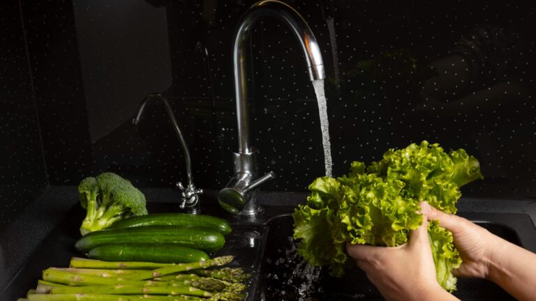 Person washing vegetables under running water